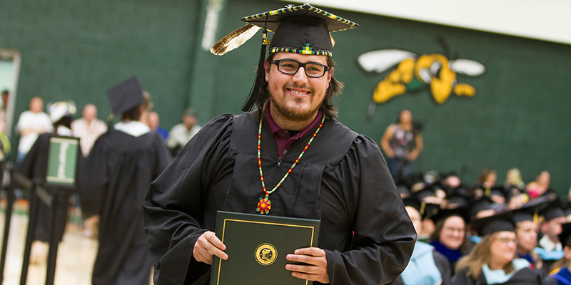 A man shows off his diploma after graduating. 