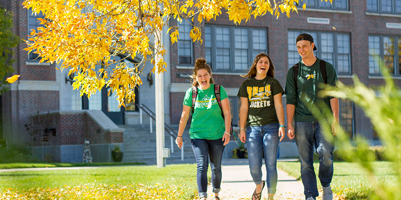Three students walk in front of Woodburn Hall.