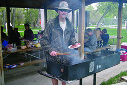 Man grabbing a hot dog at a picnic.