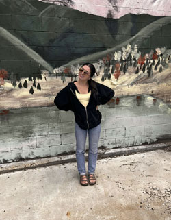 Margo Bertsch posing in front of a mural.