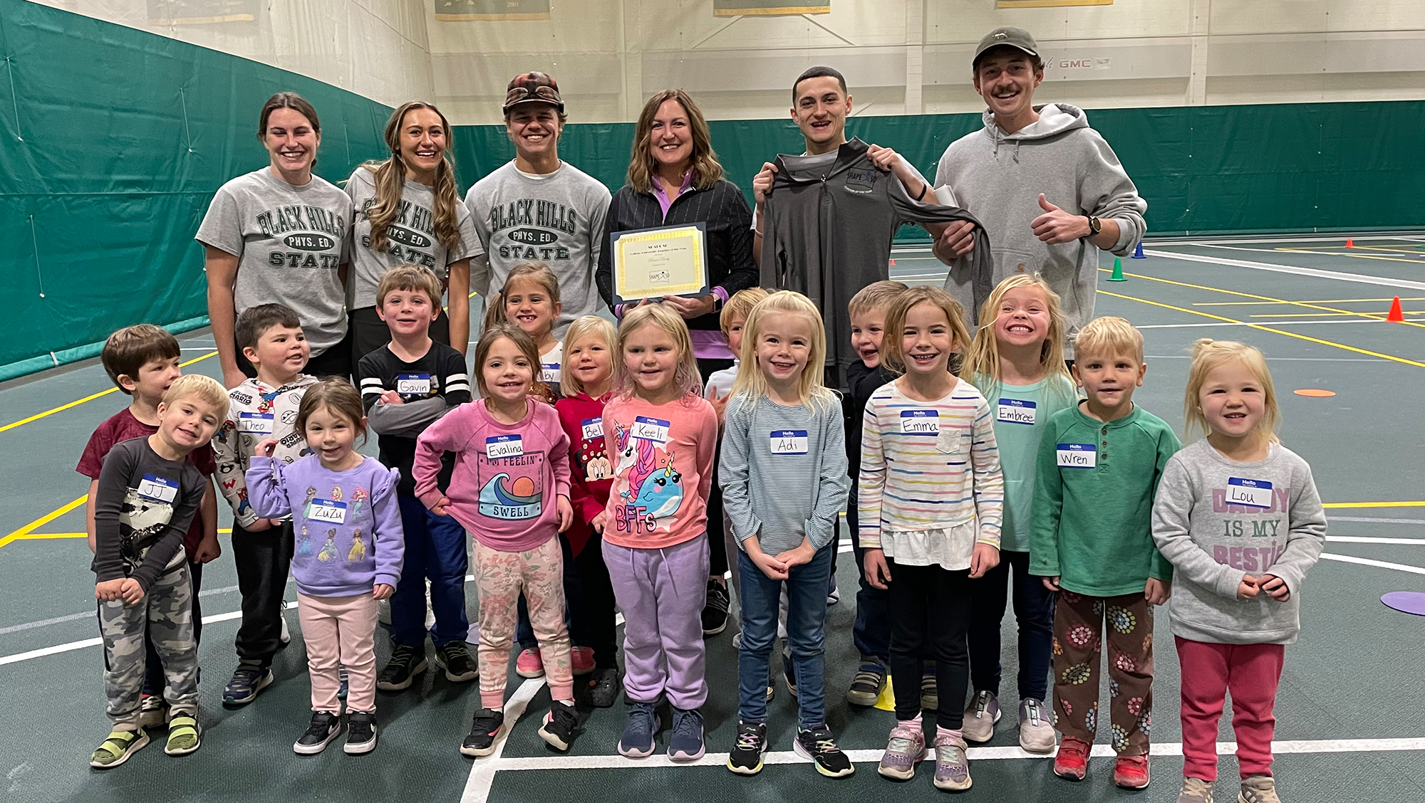Dr. Breon Darby holding award with BHSU Students and Preschool class.