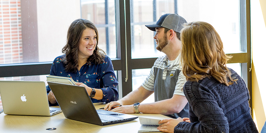 Three students study at a table.