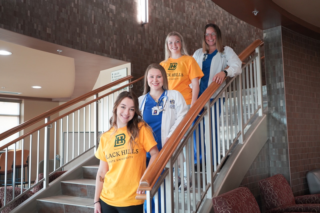 Four female nursing students standing on staircase.