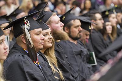 A group of people sit at commencement, waiting their turn to walk.
