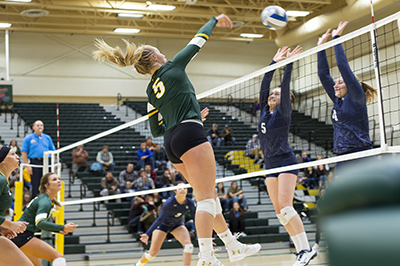 A BHSU volleyball player spikes the ball at the other team.