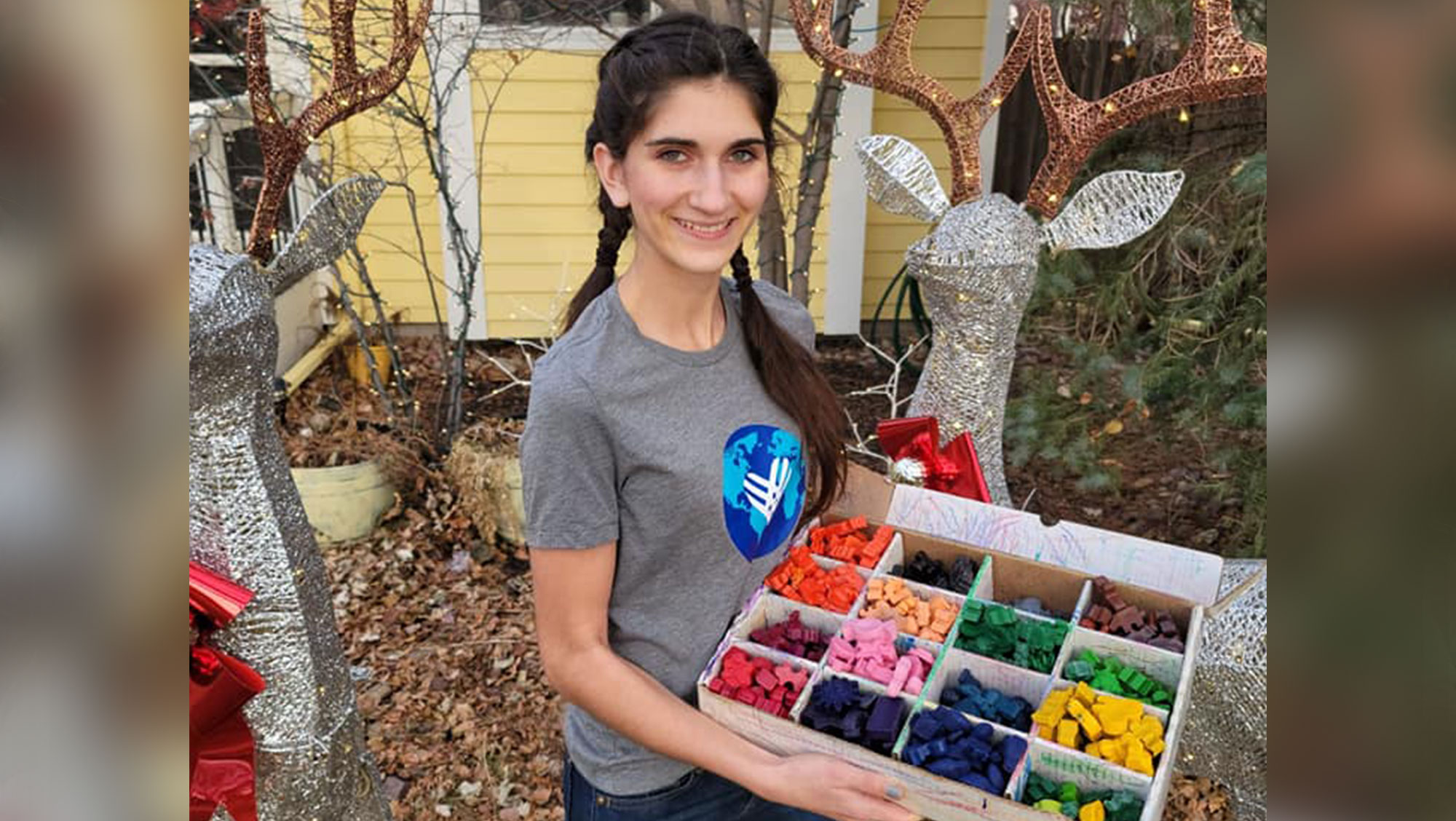 Abby Neff posing with a box of crayons she created through her nonprofit Recycled Rainbows.