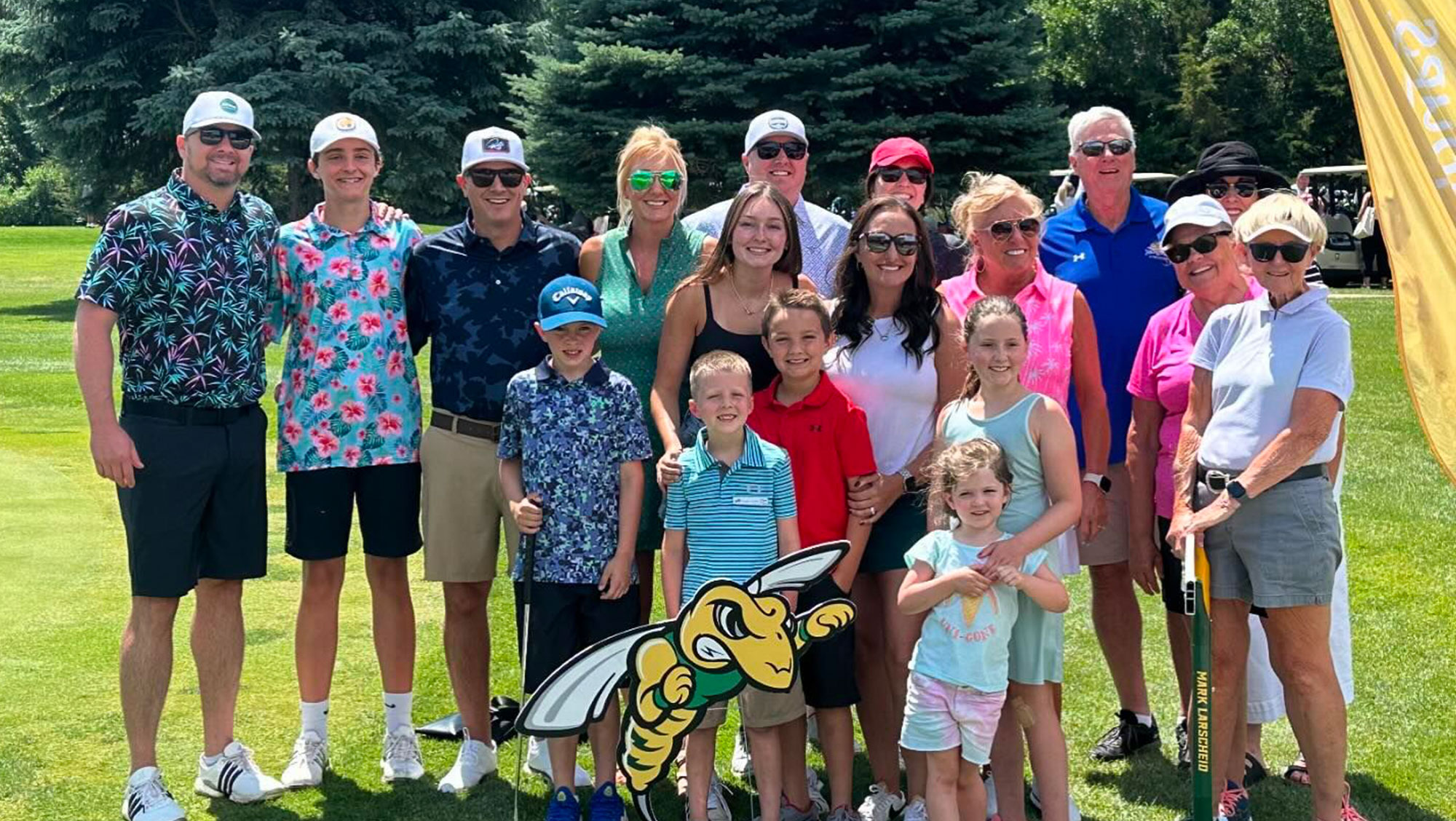 The family of Mark Larscheid posing together on a sunny day at a golf course, accompanied by cutout of the BHSU mascot Sting. This image was taken at the 23rd Annual Mark Larscheid Memorial Golf Tournament which was held at Spearfish Canyon Golf Club on July 6. 