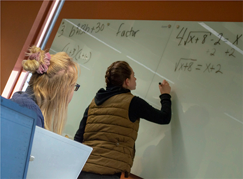 Emma Thomas writes on a whiteboard.