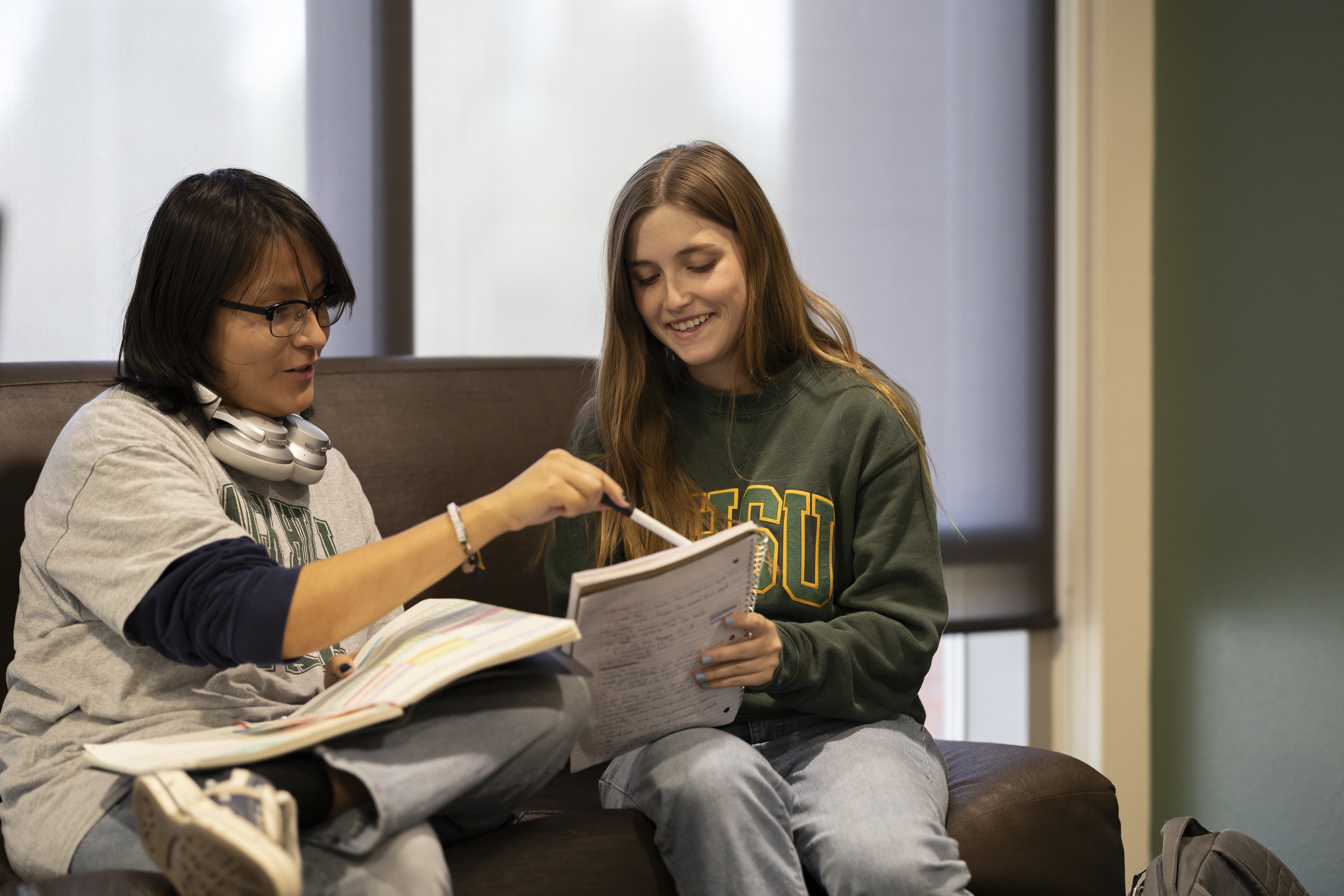 Two BHSU Pre-Respiratory Therapy students sit together on a couch while working on a project.