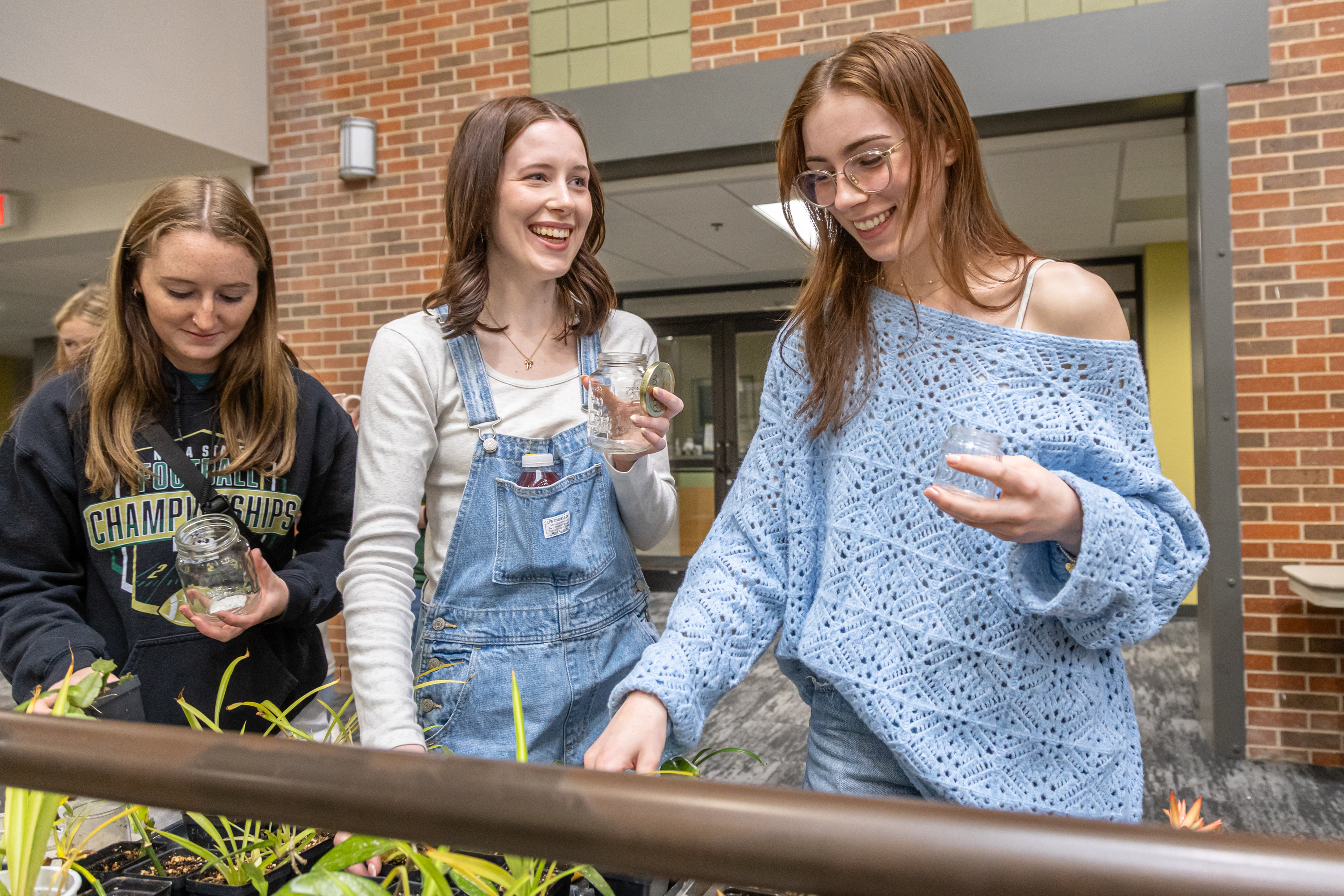 Three students plant plants at the annual Earth Day Festival.