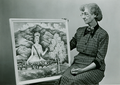 Black and white image of Mar Gretta on the right with one of her paintings on the left.
