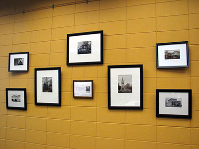Display of seven Williams J. Collin's photographs on a yellow wall.