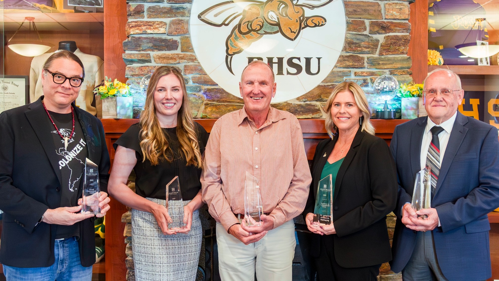 Five alumni smile with their awards