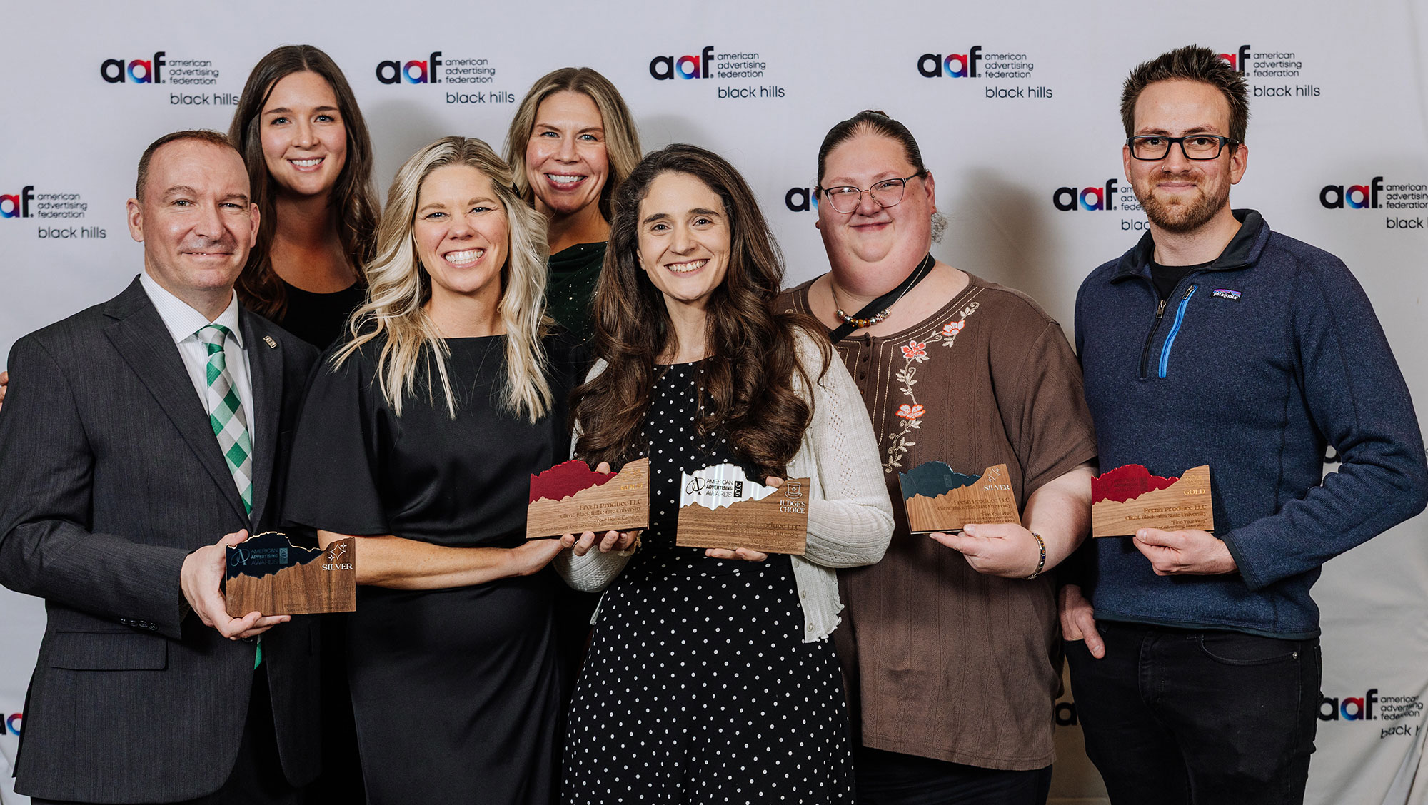 Several people stand in front of a backdrop that says 
