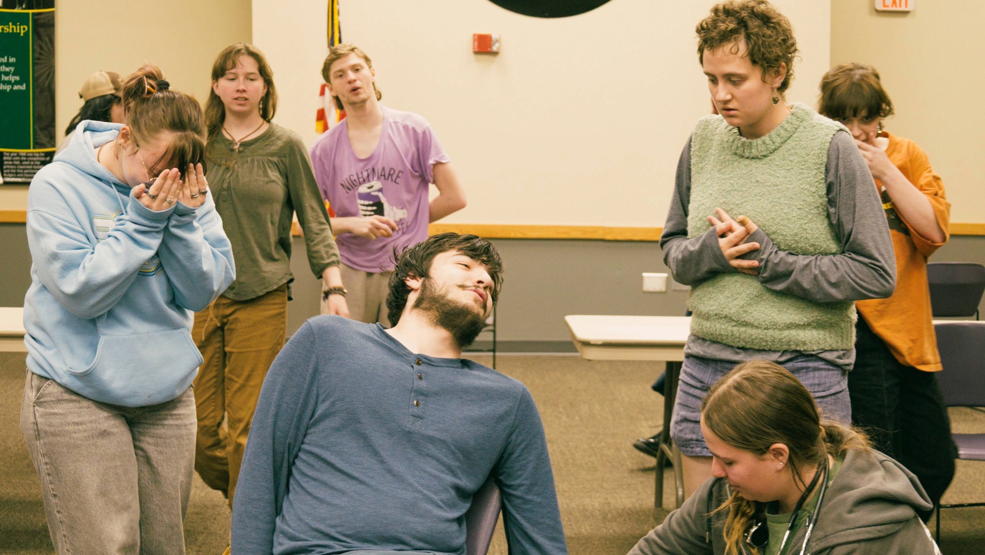 Students rehearsing for a play all stand around their peer pretending to have been murdered.