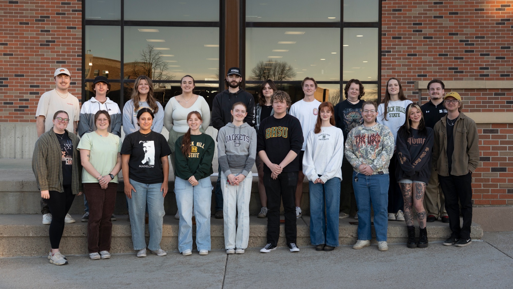 an organized group of students stand on the stairs while smiling for the camera