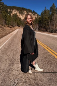 Graduate Mackenzie Gill smiles at the camera wearing her cap and gown