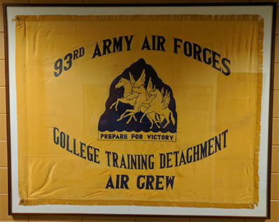 Yellow flag displaying text that says "93rd Army Airforces College Trainng Detachment Air Crew" and four horses with wings in the middle.